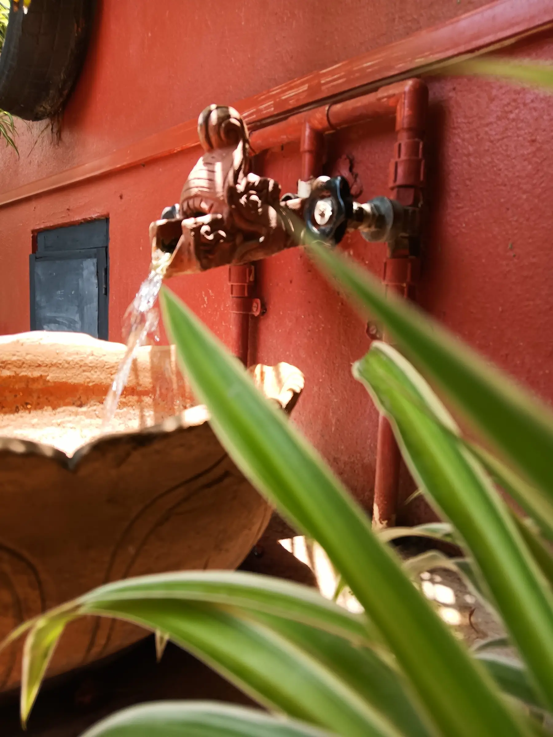 Traditional brass water spout on a terracotta wall