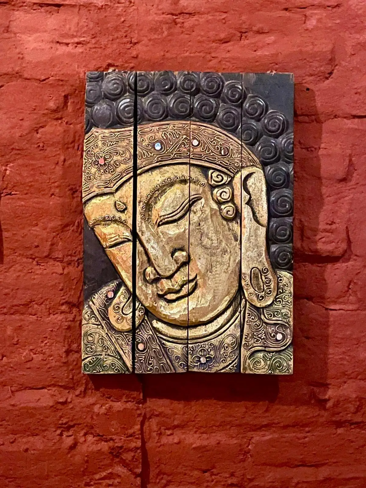 Carved Buddha wall art on a terracotta brick wall