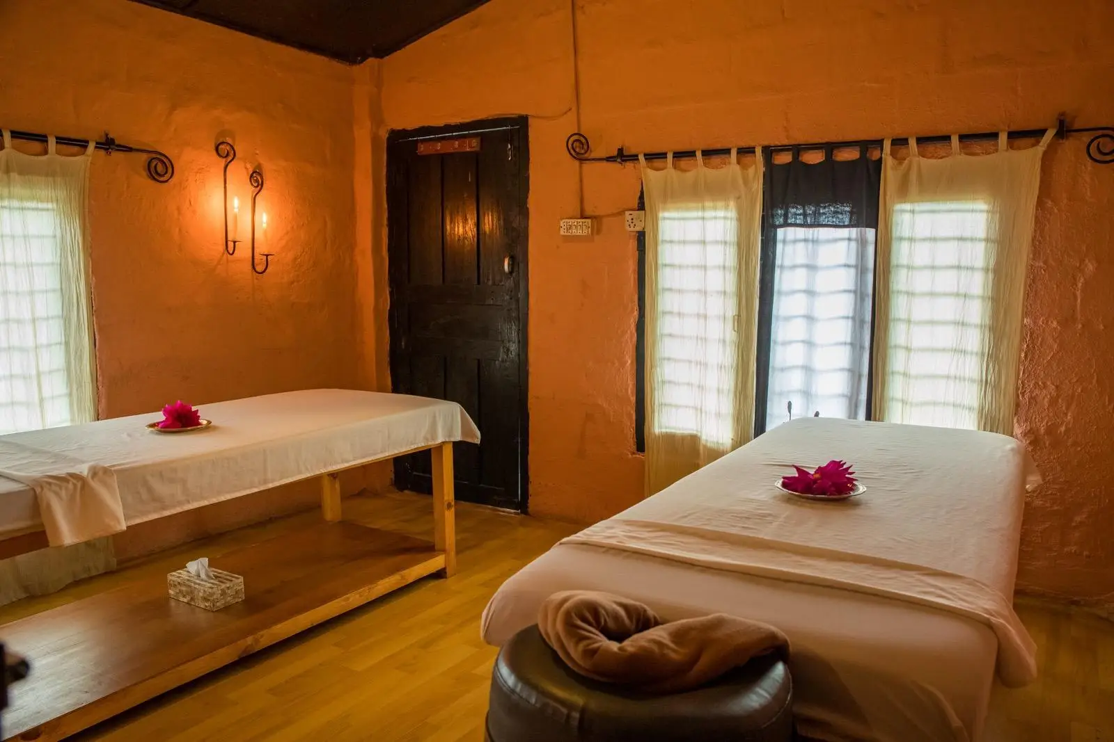 Couples treatment suite with terracotta walls and wooden floor