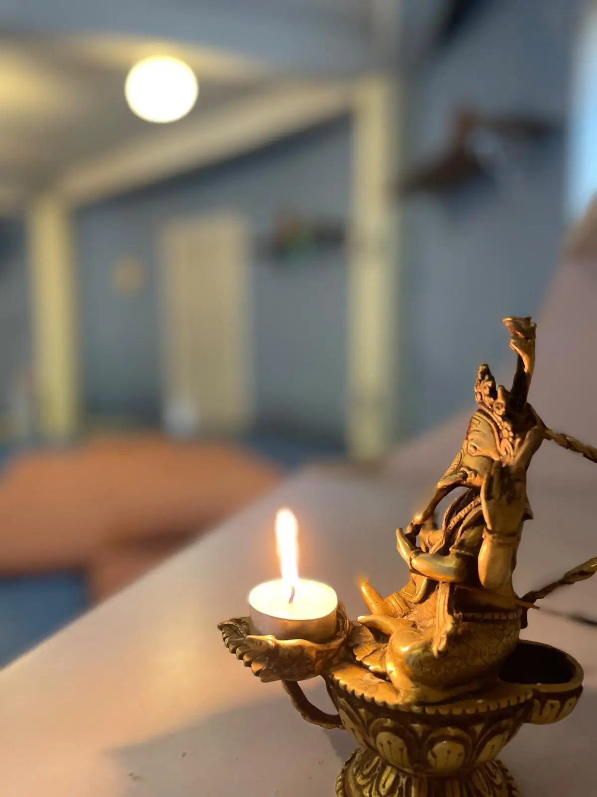 Brass Ganesha oil lamp with a lit flame