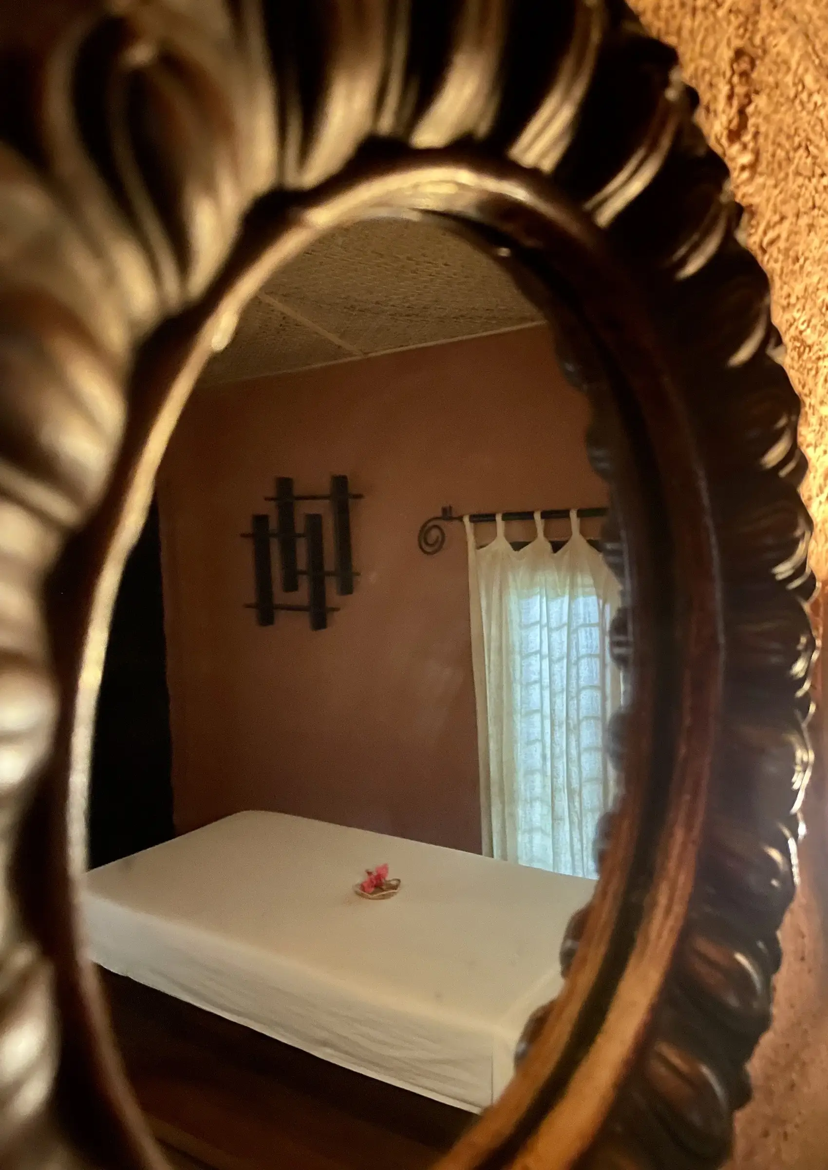 Treatment bed reflected in a carved wooden mirror