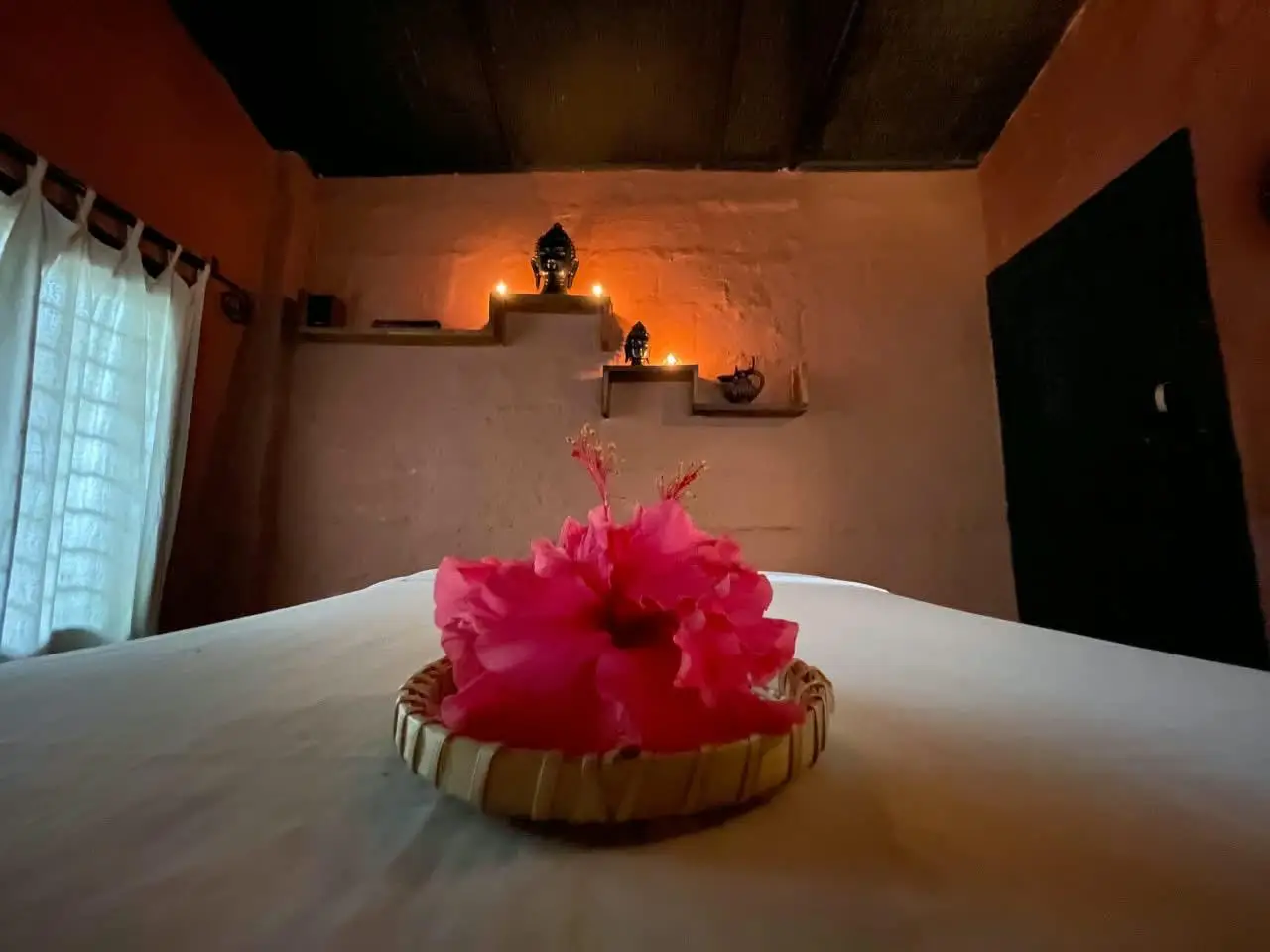 Treatment bed with fresh flowers and candlelit shelves