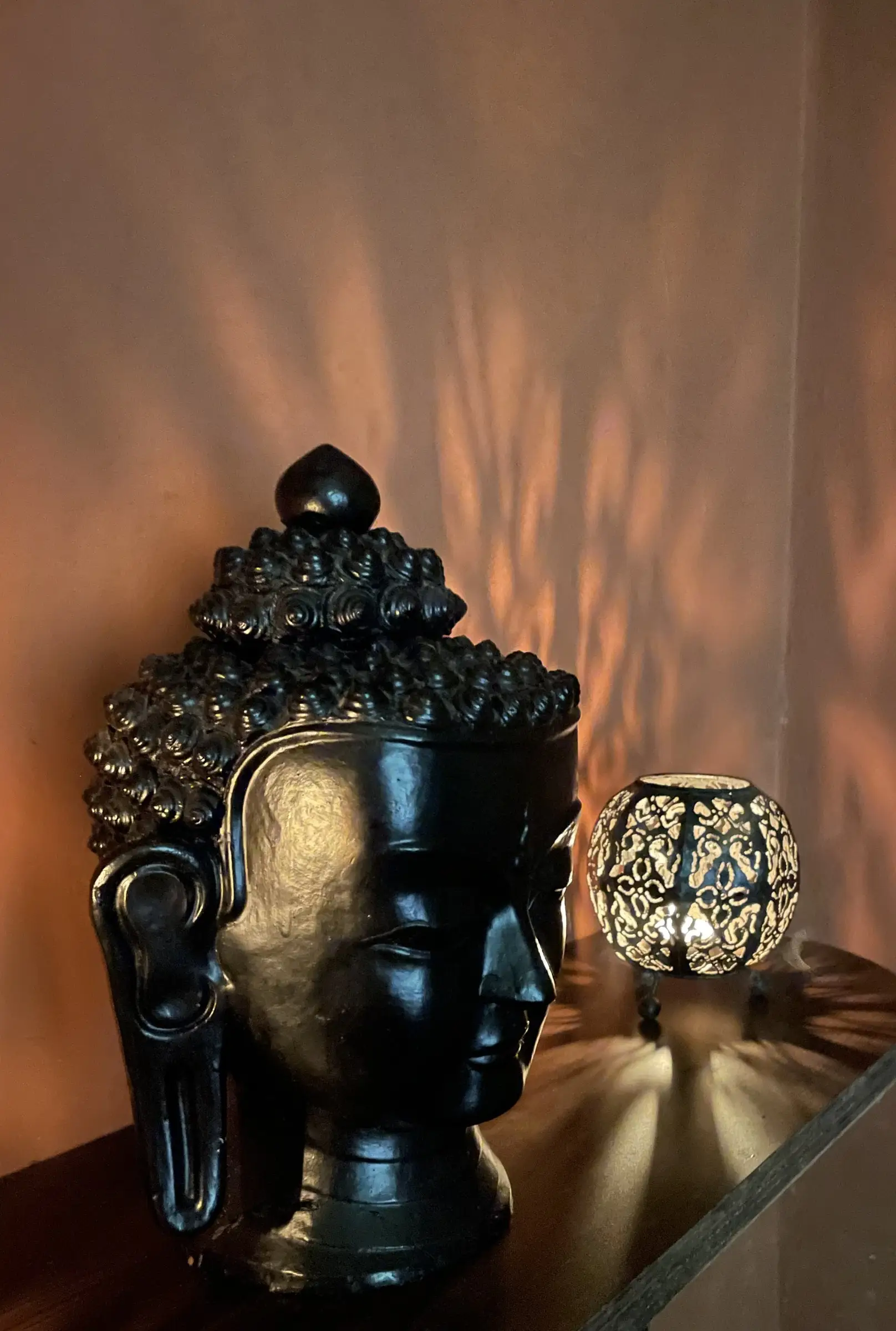 Buddha head sculpture and a patterned lantern in warm light at Jiva Spa