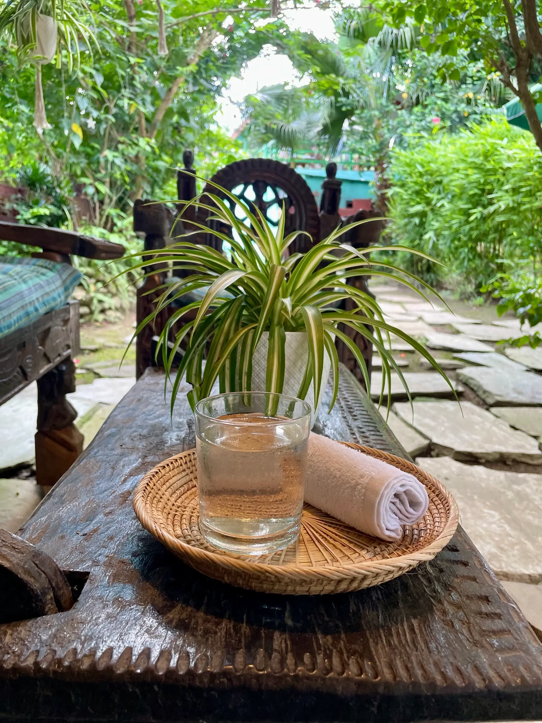 Glass of water and a fresh towel on a carved wooden bench in the garden